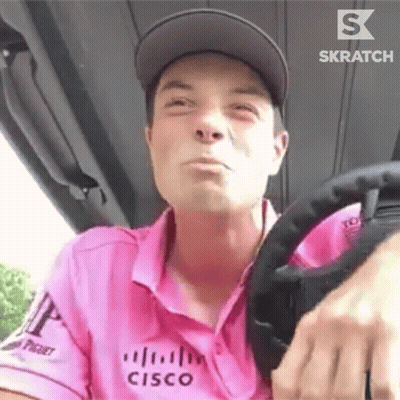 A Man In A Pink Shirt Is Driving A Golf Cart . GIF