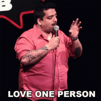 A Man In A Pink Shirt Is Holding A Microphone With The Words Love One Person Above Him GIF