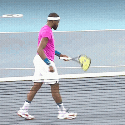 A Man In A Pink Shirt Is Holding A Tennis Racket GIF