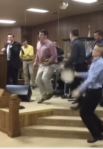 A Man In A Pink Shirt Is Jumping In The Air While Playing Drums GIF