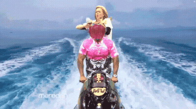 a man in a pink shirt is riding a jet ski in the water