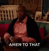 A Man In A Pink Shirt Is Sitting On A Couch Drinking A Glass Of Wine And Says Amen To That . GIF