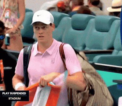A Man In A Pink Shirt Is Standing In A Stadium That Is Suspended GIF