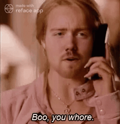 A Man In A Pink Shirt Is Talking On A Cell Phone And Says Boo , You Whore . GIF
