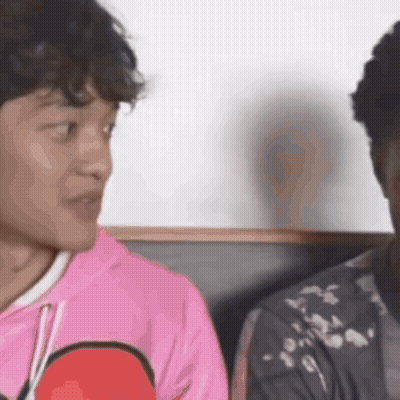 A Man In A Pink Shirt Is Talking To Another Man In A Black Jacket . GIF