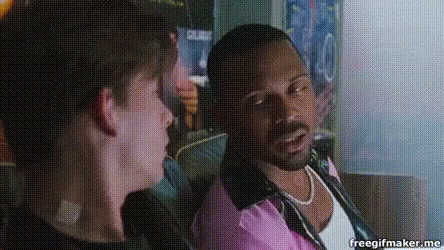 A Man In A Pink Shirt Is Talking To Another Man In A Black Shirt GIF