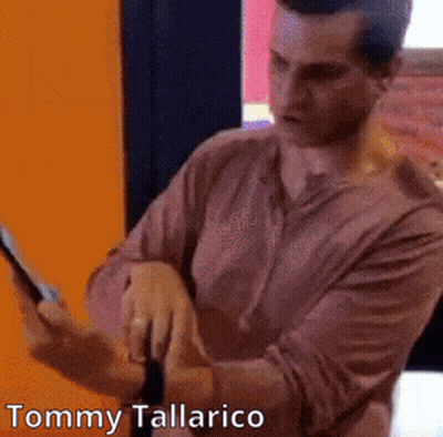 A Man In A Pink Shirt Is Using A Tablet With The Name Tommy Tallarico On The Bottom GIF