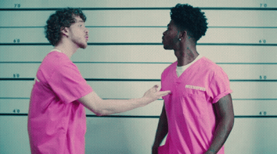A Man In A Pink Shirt With A Tattoo On His Neck Stands Next To Another Man In A Pink Shirt GIF