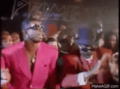 A Man In A Pink Suit And A Man In A Red Suit Are Dancing In Front Of A Crowd . GIF