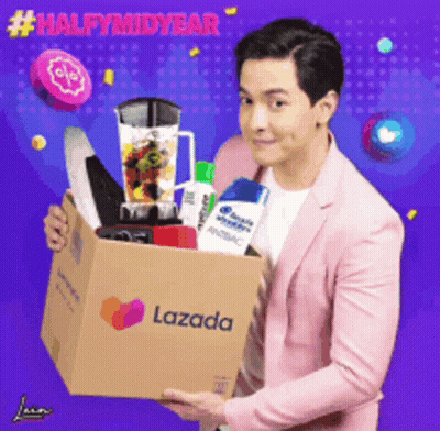 A Man In A Pink Suit Is Holding A Lazada Box Full Of Items GIF