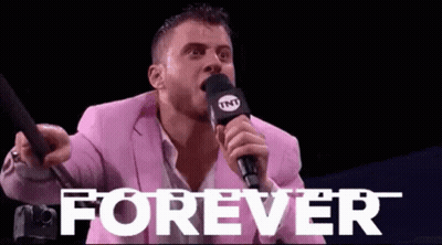 A Man In A Pink Suit Is Holding A Microphone And Shouting Into It . GIF