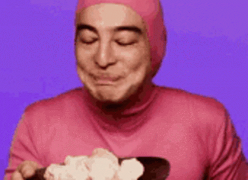 A Man In A Pink Suit Is Smiling And Making A Funny Face . GIF