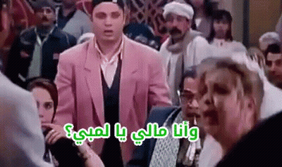 A Man In A Pink Suit Is Standing In A Crowd Of People And Talking To A Woman . GIF