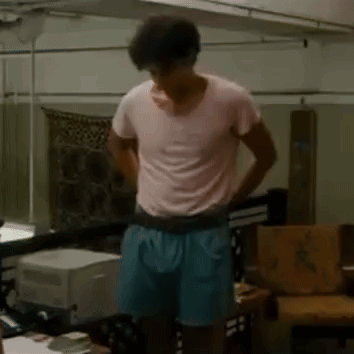 Man In Pink T-Shirt And Blue Shorts In Living Room GIF