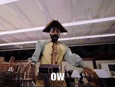 A Man In A Pirate Costume Is Standing In A Room With The Word Ow Written On The Screen Behind Him GIF