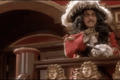 A Man In A Pirate Costume Is Standing On A Balcony With A Sword . GIF