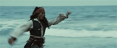 A Man In A Pirate Costume Is Standing On A Beach In Front Of The Ocean . GIF