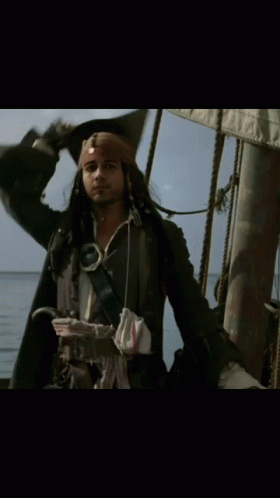 A Man In A Pirate Costume Is Standing On A Boat GIF