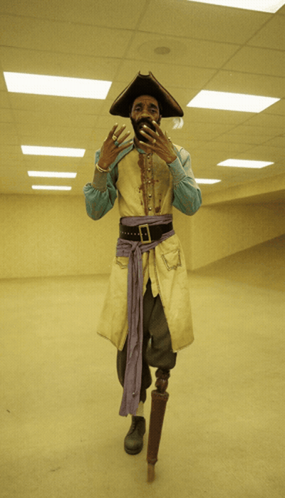 A Man In A Pirate Costume With A Prosthetic Leg Stands In An Empty Room GIF