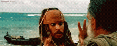 a man in a pirate outfit is talking to another man on the beach .