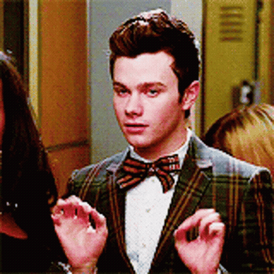 A Man In A Plaid Jacket And Bow Tie Is Talking To A Woman GIF
