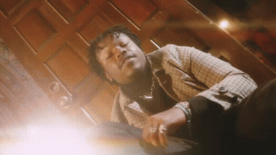 A Man In A Plaid Jacket Is Laying Down In Front Of A Wooden Door . GIF