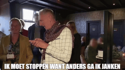 A Man In A Plaid Jacket Is Standing In Front Of A Group Of People In A Room . GIF