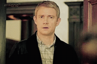 A Man In A Plaid Shirt And A Black Jacket Is Standing In Front Of A Door . GIF