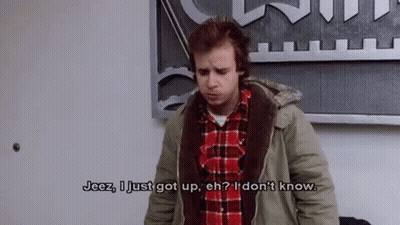 A Man In A Plaid Shirt And A Jacket Is Standing In Front Of A Wall . GIF