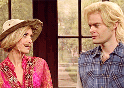 A Man In A Plaid Shirt And A Woman In A Cowboy Hat Are Looking At Each Other GIF