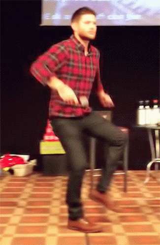 A Man In A Plaid Shirt And Black Jeans Is Dancing On A Tiled Floor GIF
