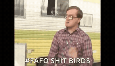 A Man In A Plaid Shirt And Glasses Is Standing In Front Of A Trailer And Talking . GIF