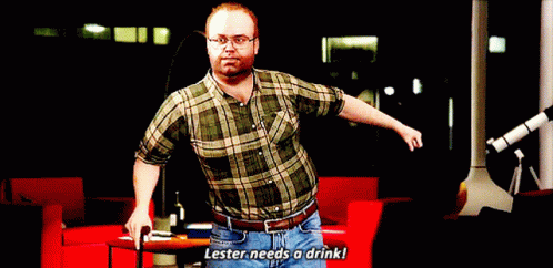 A Man In A Plaid Shirt And Jeans Says Lester Needs A Drink GIF