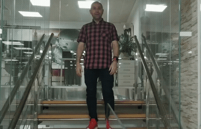 A Man In A Plaid Shirt And Red Shoes Is Walking Up A Set Of Stairs GIF