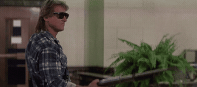A Man In A Plaid Shirt And Sunglasses Holds A Gun GIF