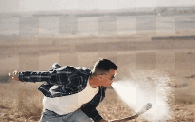 A Man In A Plaid Shirt And Sunglasses Is Throwing A Hammer In The Air GIF