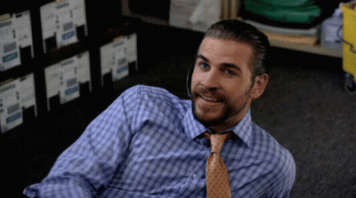 A Man In A Plaid Shirt And Tie Is Laying On The Floor Smiling GIF