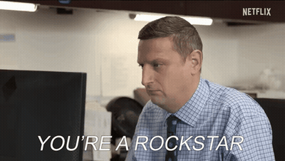 A Man In A Plaid Shirt And Tie Is Sitting At A Desk In Front Of A Computer And Talking . GIF