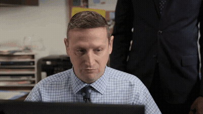 A Man In A Plaid Shirt And Tie Looks At A Computer Screen GIF