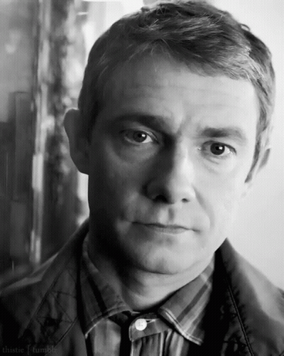 A Man In A Plaid Shirt And Tie Looks At The Camera In A Black And White Photo . GIF