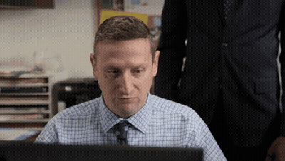 A Man In A Plaid Shirt And Tie Sits In Front Of A Laptop GIF