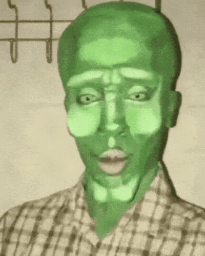 A Man In A Plaid Shirt Has A Green Face Painted On His Face . GIF