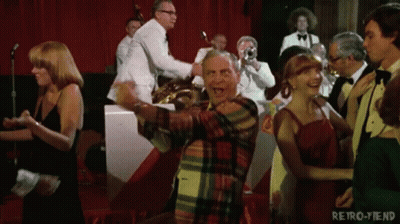 A Man In A Plaid Shirt Is Dancing In Front Of A Band With The Words Retro-Fiend On The Bottom GIF