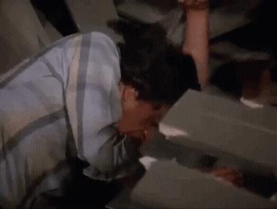 A Man In A Plaid Shirt Is Drinking From A Faucet In A Bathroom . GIF