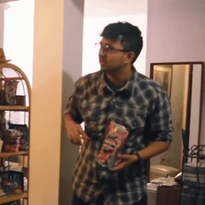 A Man In A Plaid Shirt Is Holding A Bag Of Candy GIF