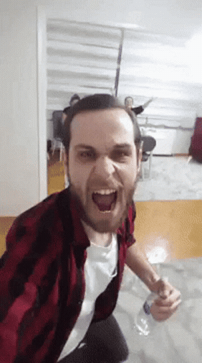 A Man In A Plaid Shirt Is Holding A Bottle Of Water GIF