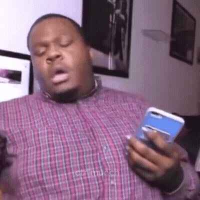 A Man In A Plaid Shirt Is Holding A Cell Phone In His Hand And Making A Funny Face . GIF