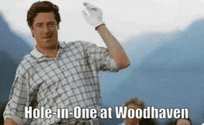 A Man In A Plaid Shirt Is Holding A Golf Club And Says Hole In One At Woodhaven GIF