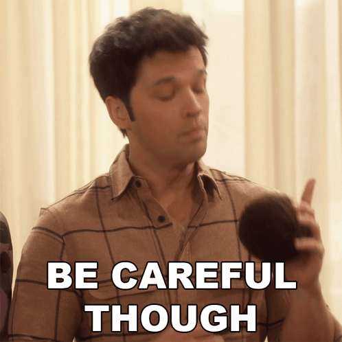 A Man In A Plaid Shirt Is Holding A Microphone And Says Be Careful Though GIF