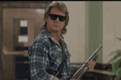 A Man In A Plaid Shirt Is Holding A Shotgun GIF